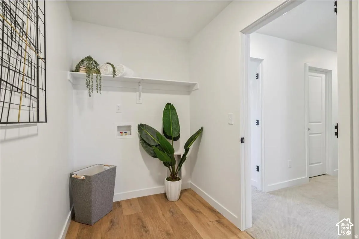 Dedicated laundry space with wood-finish flooring and a built-in storage shelf