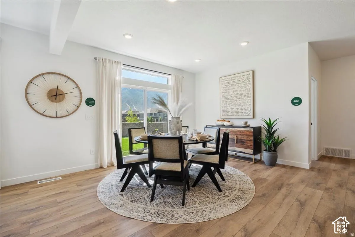 Light wood-finish flooring, recessed lighting, and a large window with white drapery