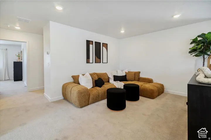 Recessed lighting illuminates a carpeted room with a wide doorway