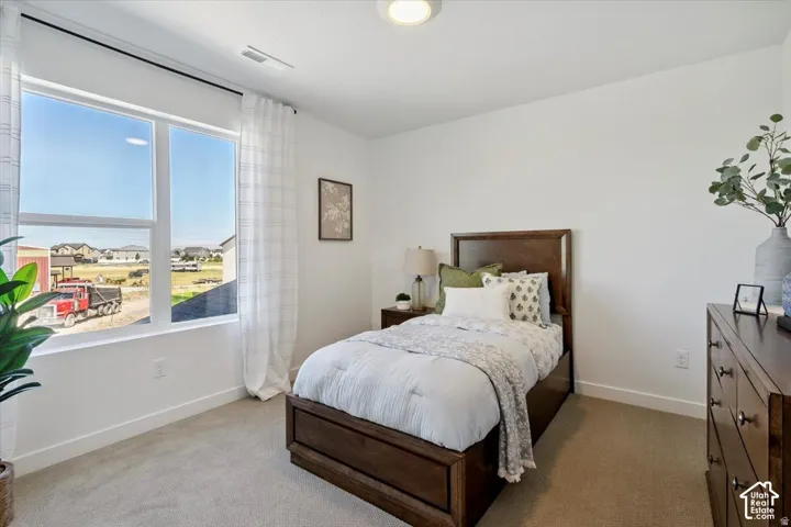 Recessed ceiling lighting, large window with ample natural light, neutral carpeting, and a built-in closet door