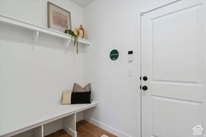 Built-in bench with cubby storage, wood-finish flooring, and a solid-panel door with matte black hardware