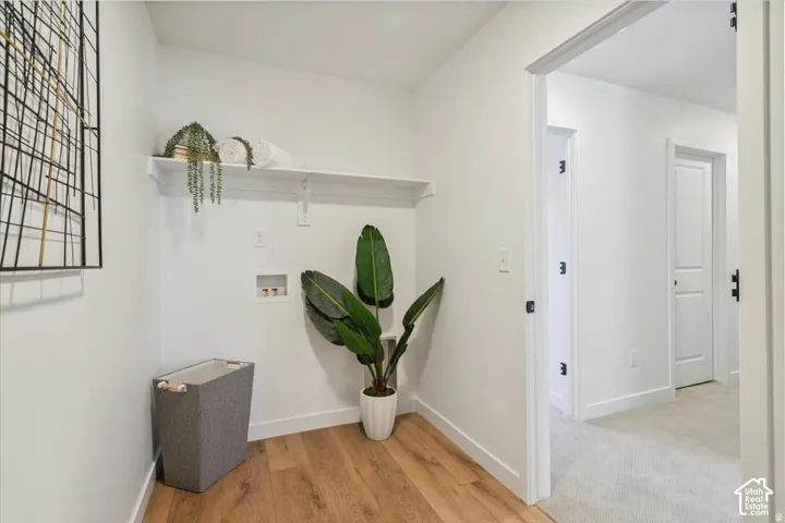 Dedicated laundry space with wood-finish flooring and a built-in storage shelf