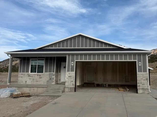 Exterior featuring horizontal siding, stone facade accents, a dark shingle roof, white trim, and a concrete driveway