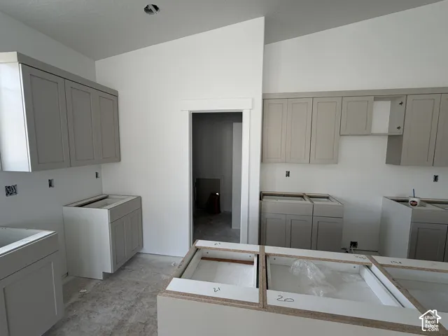 Grey shaker-style cabinetry with upper and lower installations, a kitchen island base, and a white interior wall finish