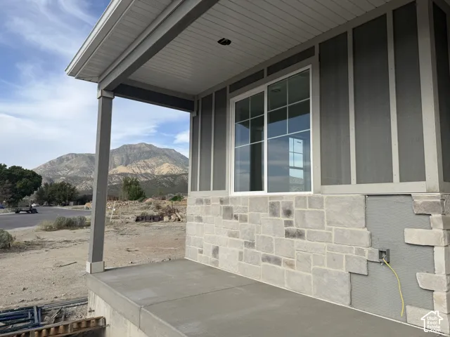 Concrete porch with support columns, stone facade, and board and batten siding