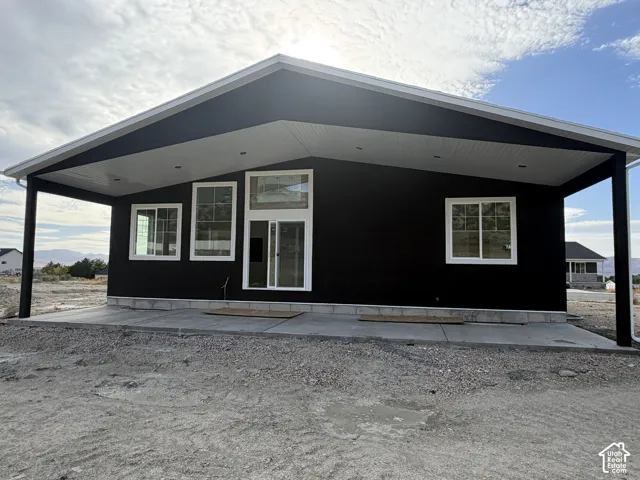 Contemporary exterior with dark stucco, white window frames, and a covered concrete patio