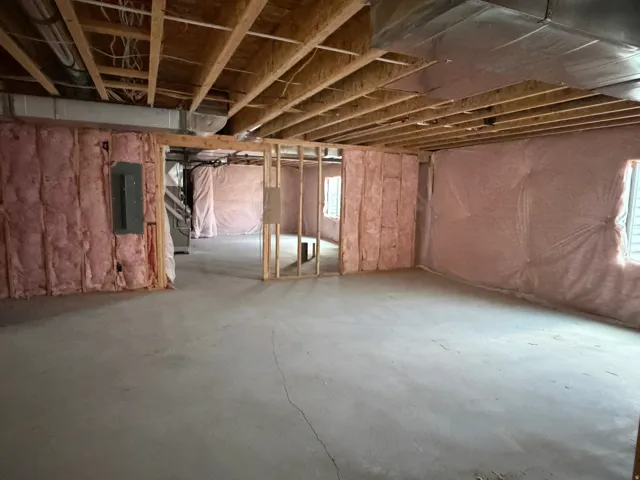 Unfinished basement featuring exposed wood joists, concrete flooring, and insulated perimeter walls