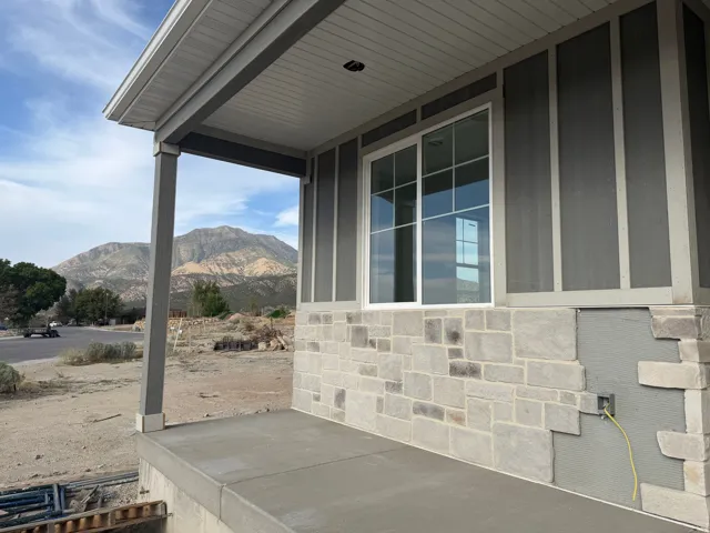 Concrete porch with support columns, stone facade, and board and batten siding