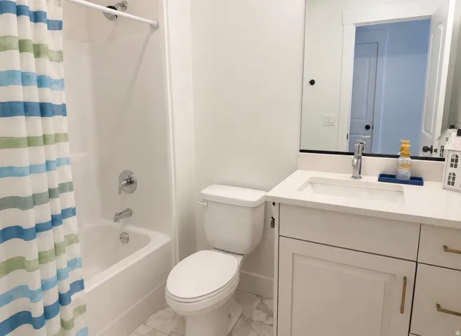 Bathroom featuring a white vanity with gold-finish hardware, integrated sink, and a framed mirror