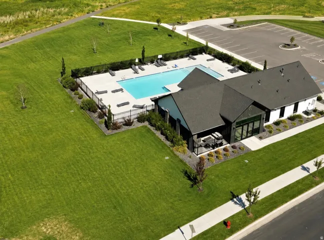 Modern clubhouse with a dark shingle roof, a fenced swimming pool, and an adjacent parking area