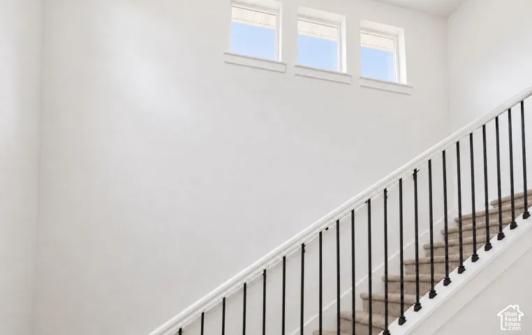 Staircase featuring black metal balusters and a white handrail