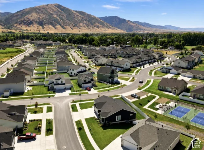 Mountain-backed community featuring a mix of single-family homes and townhomes, landscaped common areas, and recreational courts