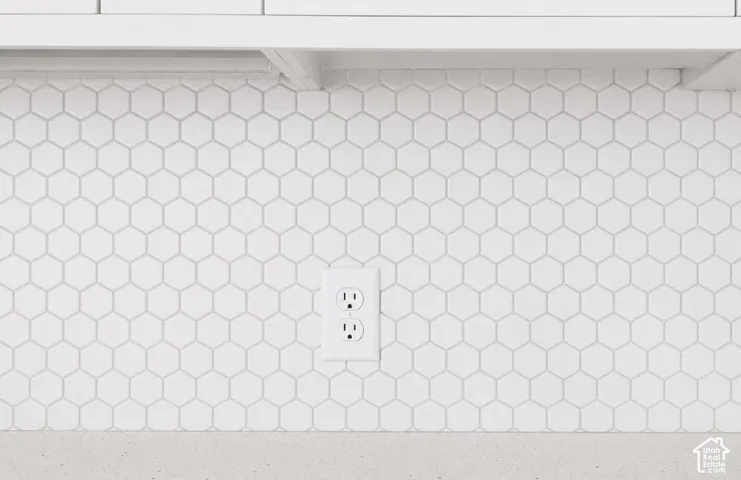 White hexagonal tile backsplash, light-toned countertop, and white cabinetry