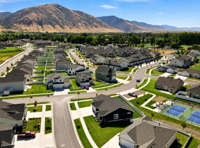 Mountain-backed community featuring a mix of single-family homes and townhomes, landscaped common areas, and recreational courts
