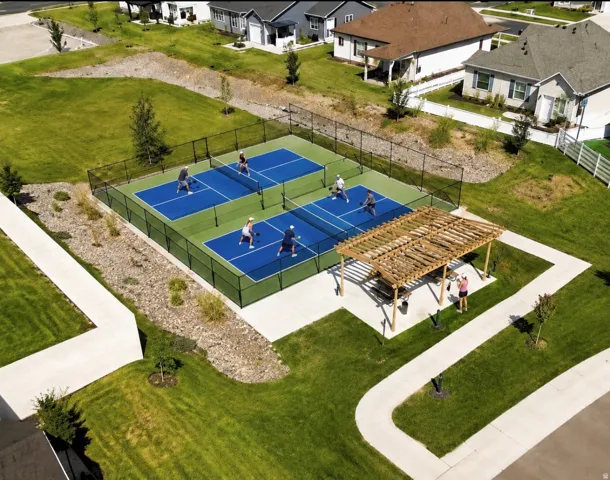 Two pickleball courts with black perimeter fencing