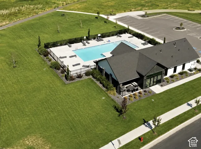 Modern clubhouse with a dark shingle roof, a fenced swimming pool, and an adjacent parking area