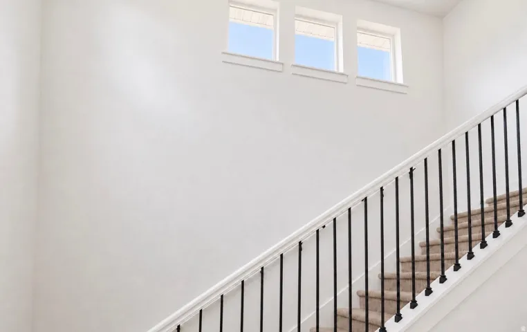 Staircase featuring black metal balusters and a white handrail