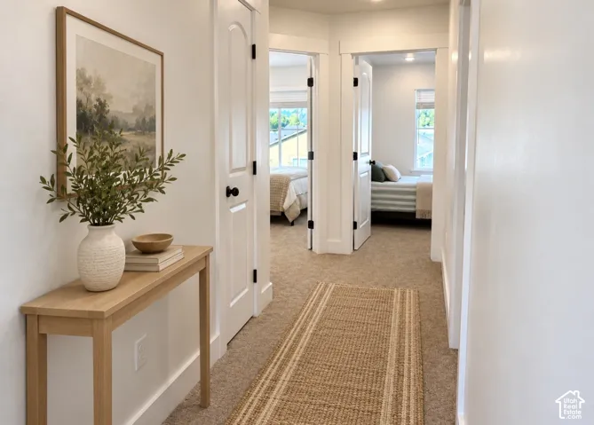 Hallway featuring neutral wall-to-wall carpeting, white arched interior doors, and white door casings