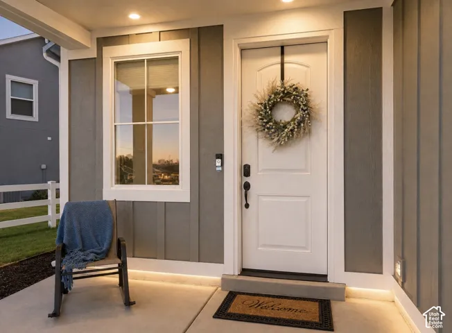 Front entry featuring a white paneled door, black hardware, white trim, recessed lighting, and integrated accent lighting