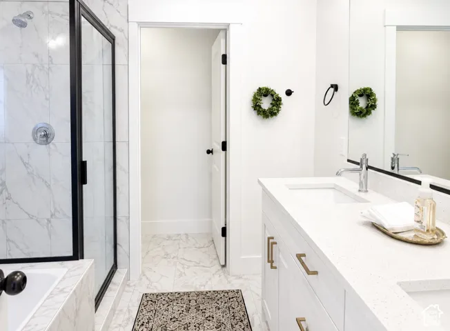 Marble-patterned tile flooring and shower surround, dual vanity with undermount sinks, bronze hardware, and a framed glass shower enclosure