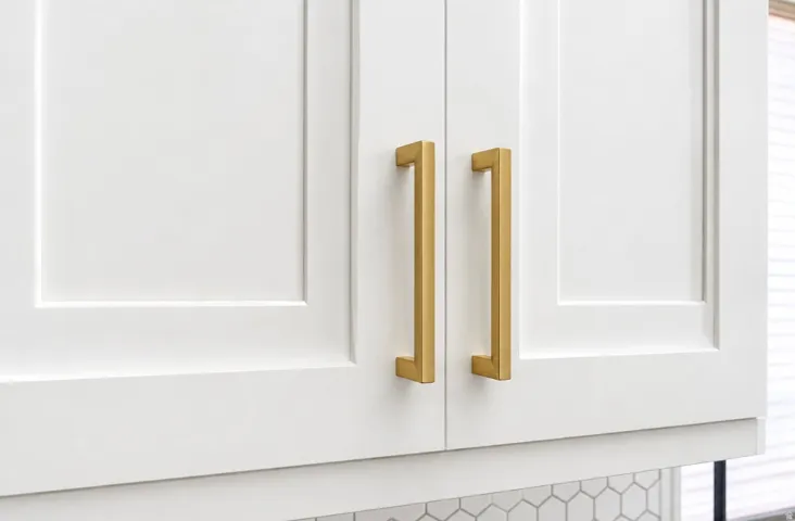 White shaker-style cabinetry with gold-tone hardware and hexagonal tile backsplash
