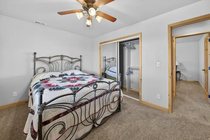 Carpeted flooring, a ceiling fan with integrated lighting, and wooden door frames