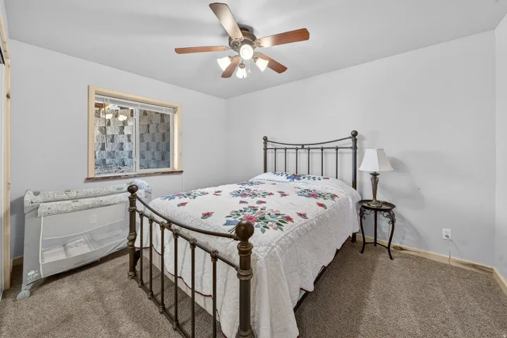 Carpeted room featuring a ceiling fan with integrated lighting, a window with a wood-finish frame, and light-colored walls