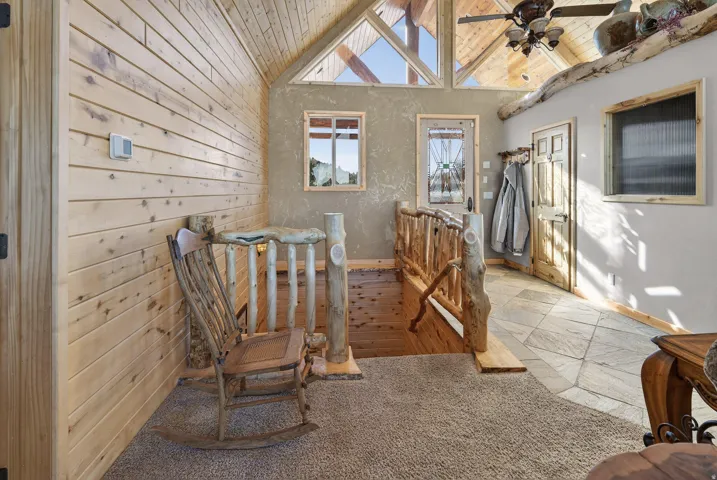 Vaulted wood-paneled ceiling, exposed wood beams, and a wood-finish railing