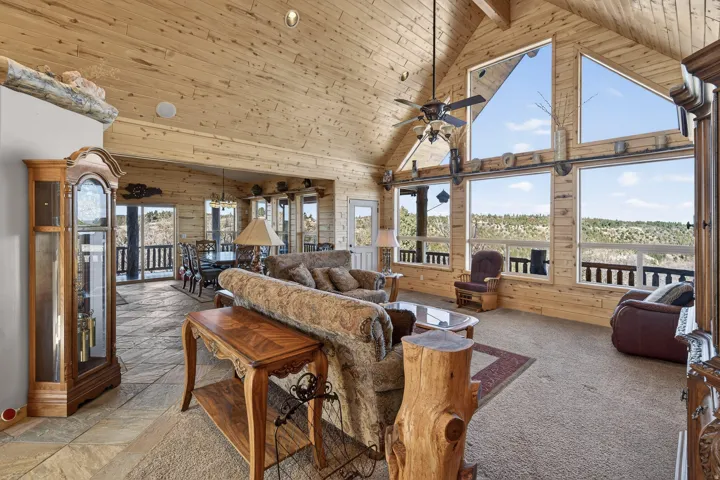 Vaulted wood-paneled ceilings, extensive window wall, wood-paneled walls, flagstone flooring, and ceiling fan