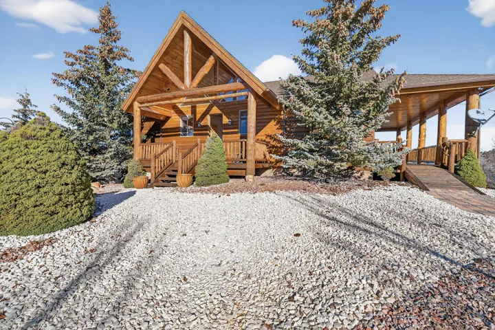 Log cabin exterior with a covered porch, wood stairs, and a ramp access