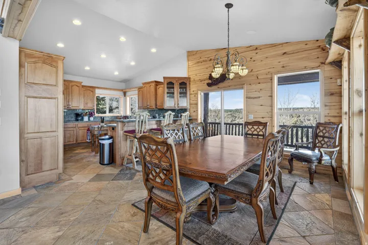 Vaulted ceiling with recessed lighting, tile flooring, wood-paneled walls, and kitchen featuring wood cabinetry