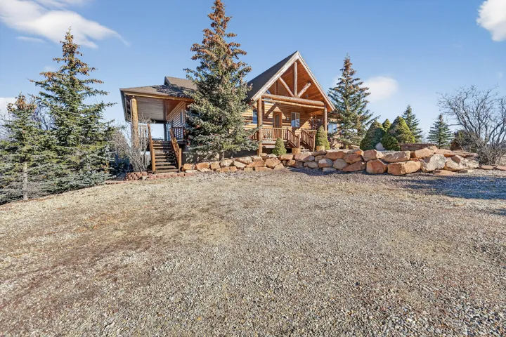 Log cabin exterior with an A-frame gable, front porch, and natural wood railings