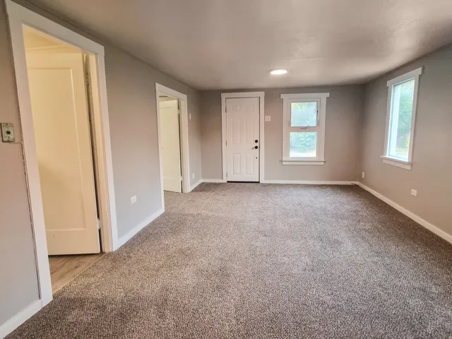 Wall-to-wall carpeting, multiple windows, and a panel door