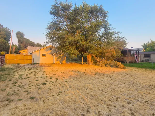 Detached shed structure, expansive yard area, wood fence, mature trees, and a raised wood deck