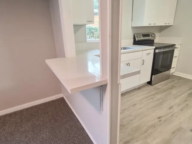 Kitchen featuring white cabinetry, stainless steel range, and light-toned countertops