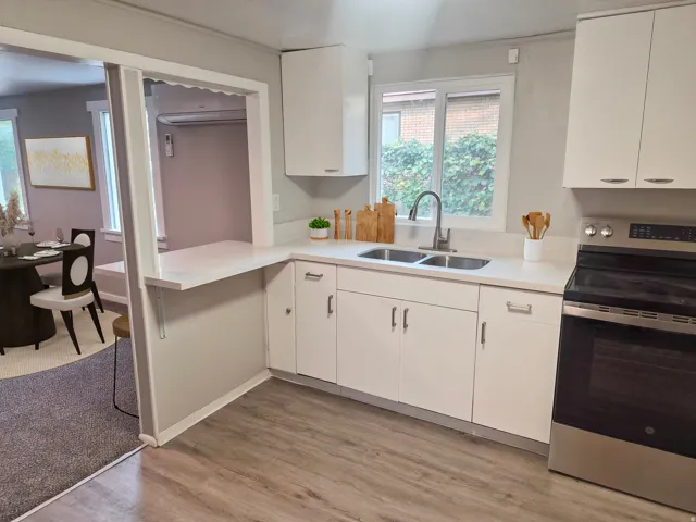 Kitchen featuring wood-finish flooring, white cabinetry, a double basin sink, and a stainless steel range
