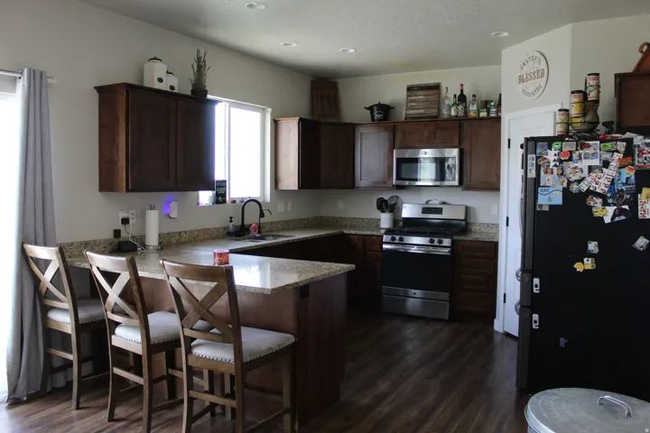Kitchen featuring wood-finish flooring, dark wood cabinetry, light-toned countertops, and stainless steel appliances