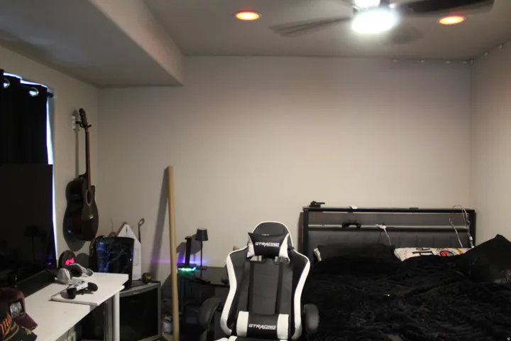 Recessed ceiling lighting, ceiling fan, and window with dark curtains