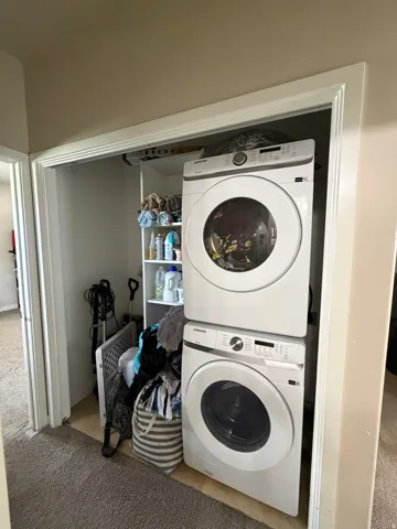 Laundry closet featuring stacked front-load machines and built-in shelving
