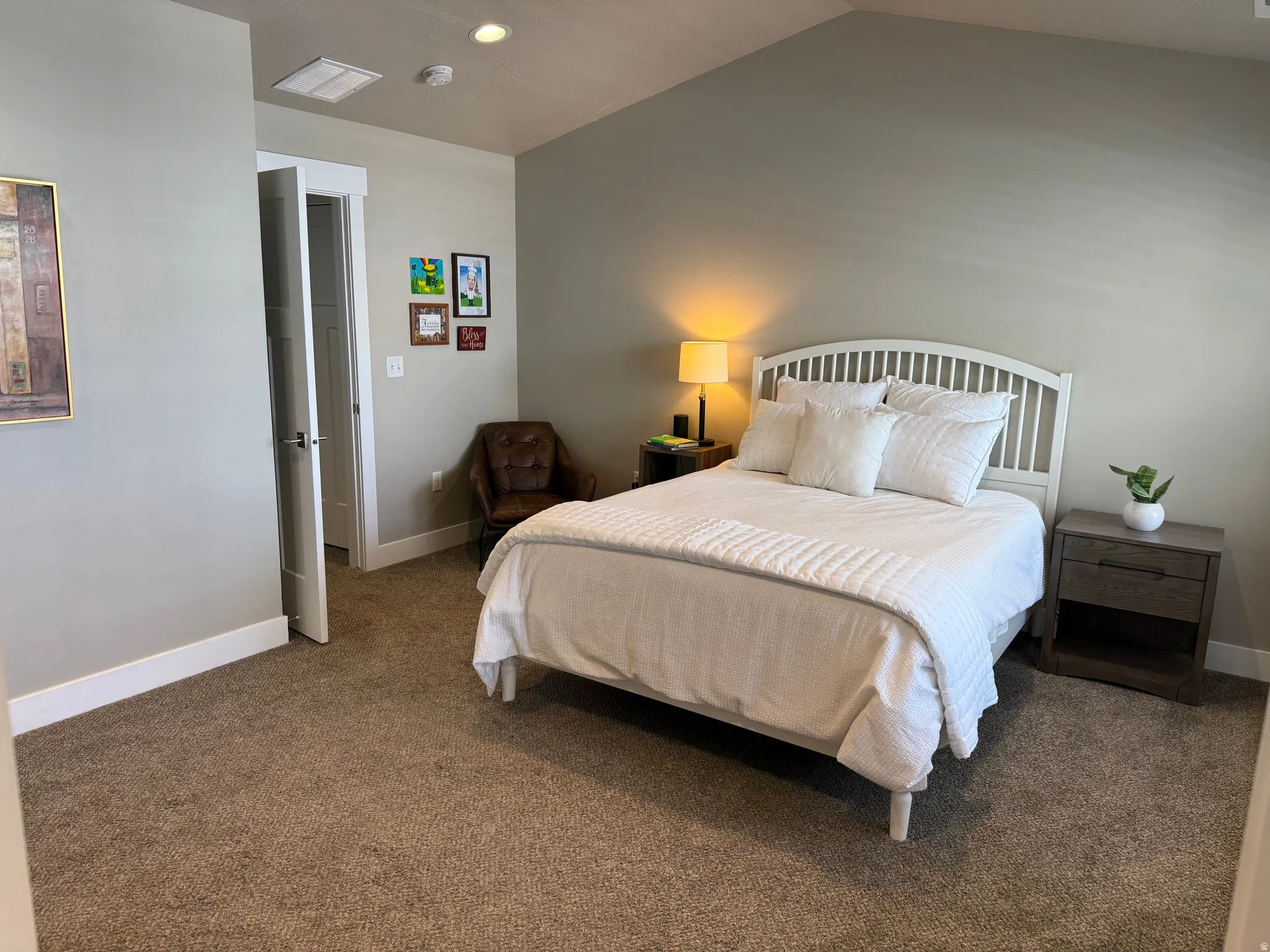 Primary suite with Carpeted bedroom featuring a vaulted ceiling, recessed lighting, and a white paneled door