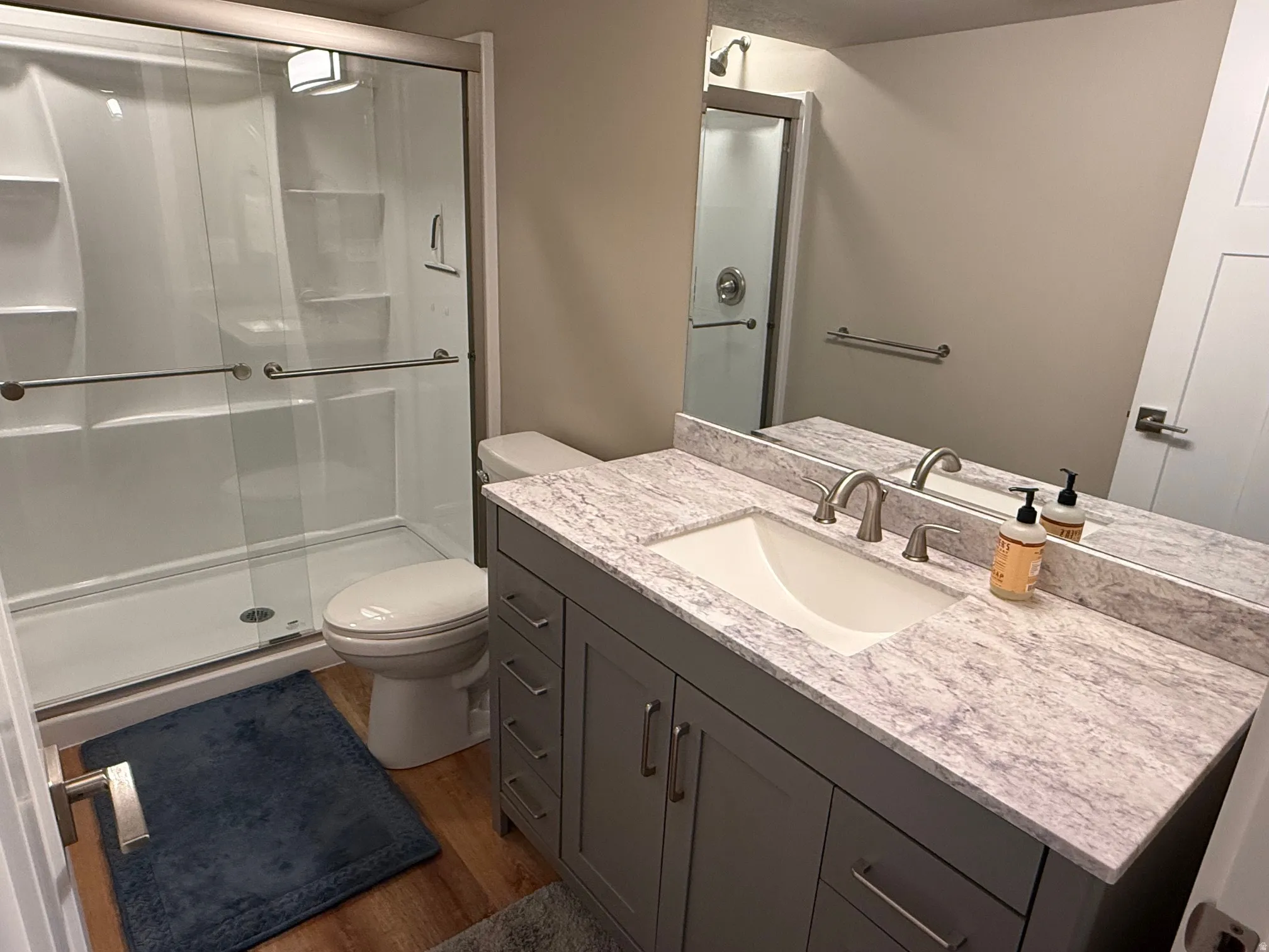 Walk-in shower with clear glass enclosure and grab bars