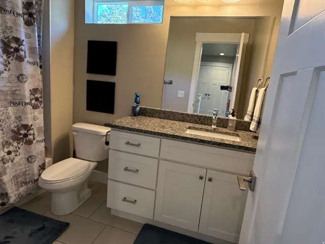 White vanity with granite-style countertop, undermount sink, and brushed nickel hardware