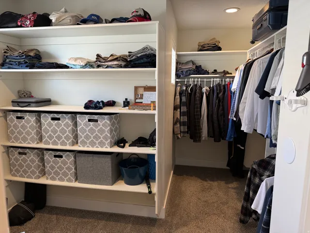 Primary Walk-in closet featuring extensive built-in shelving, multiple hanging rods, and recessed lighting