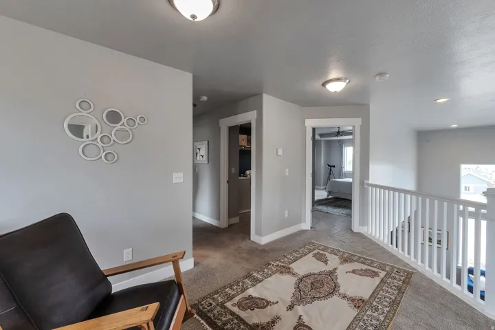 Carpeted hallway with white trim, white spindle railing, and recessed lighting