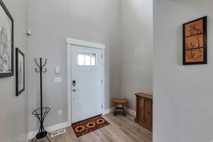 Entryway featuring a white paneled door with transom windows, a smart lock, and wood-finish flooring
