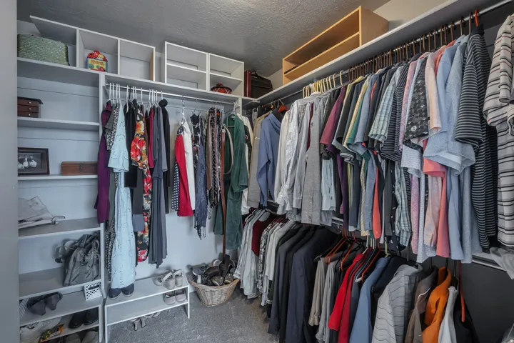 Built-in closet system featuring multiple hanging rods, open shelving, and integrated storage cubes
