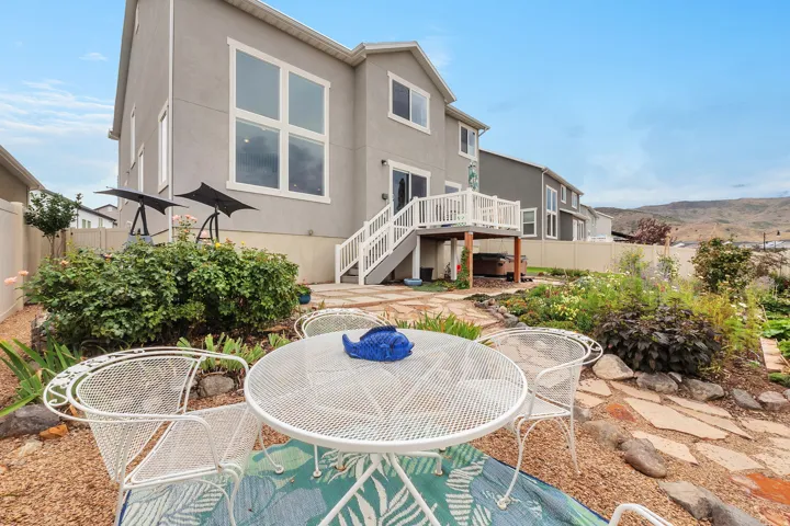 Expansive backyard featuring a multi-level deck, a stone patio area, mature landscaping, and mountain scenery