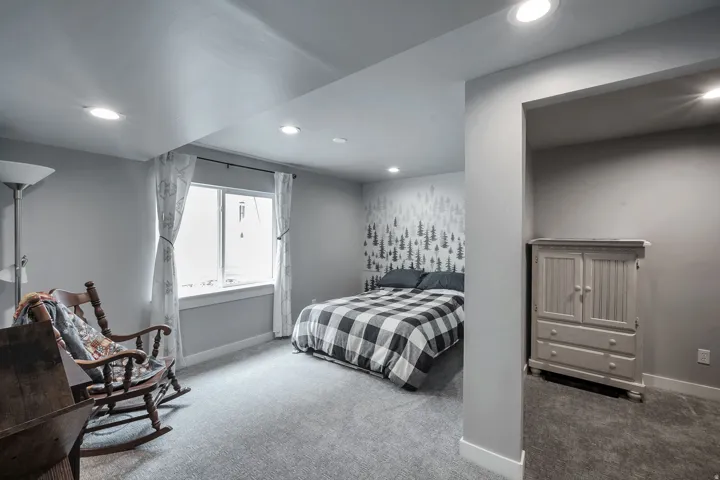 Recessed lighting, light gray wall color, wall-to-wall carpeting, and a window with white trim