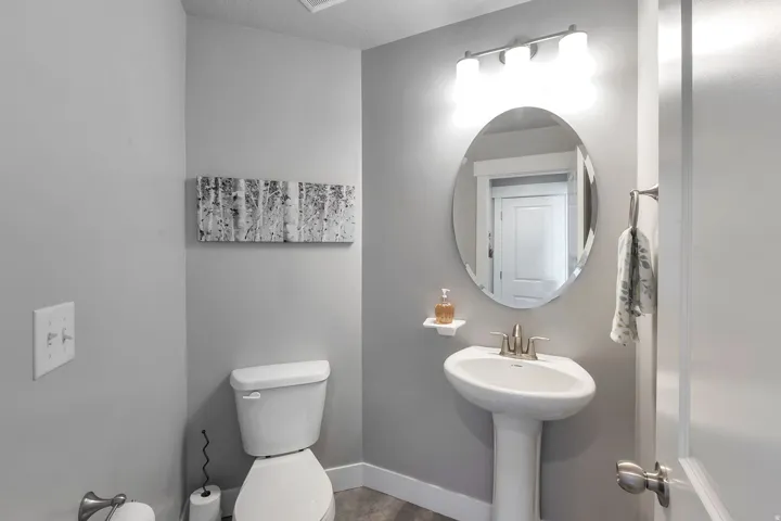 White pedestal sink with a brushed nickel faucet and an oval mirror