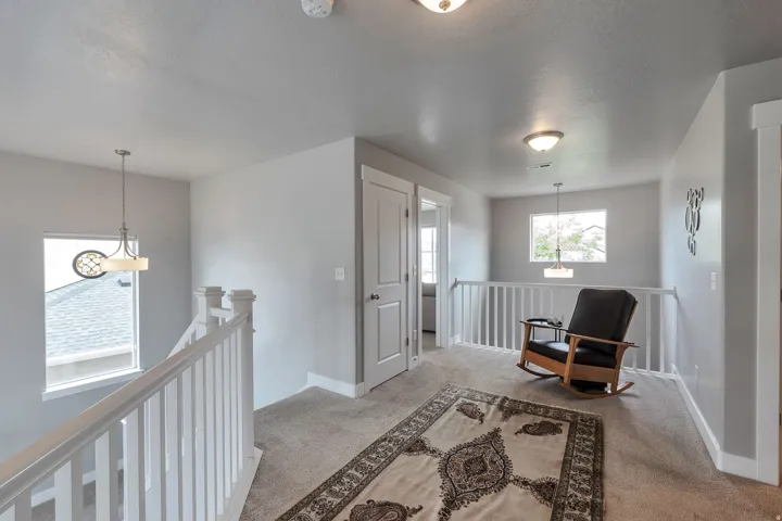 Carpeted hallway with white baluster railing and neutral wall paint